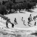 Black and white photo of people exploring an ancient Greek amphitheater by the sea.